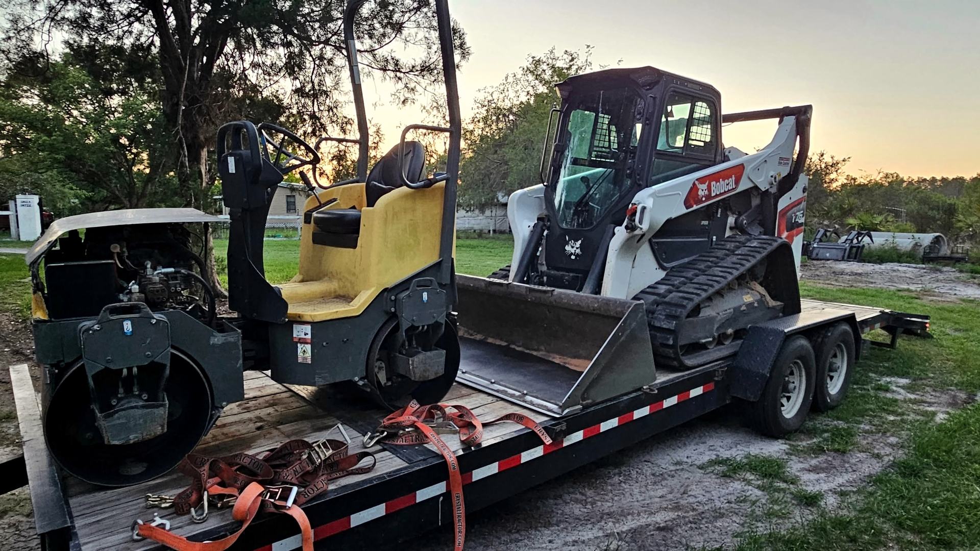 Bobcat T76, ride-on roller and milling drum loaded on the trailer at sunset