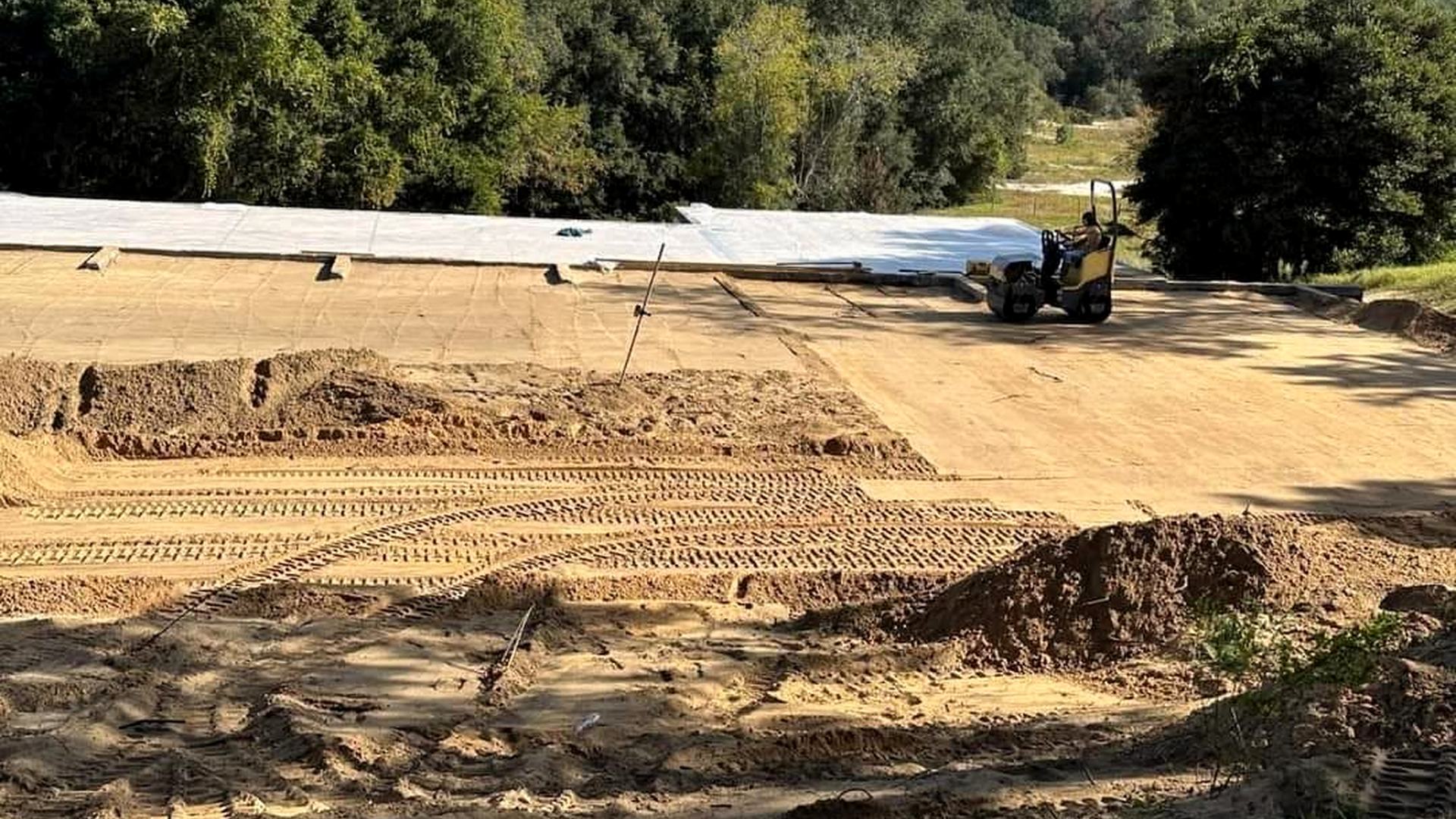 A compacted building pad with vapor barrier down and the roller working