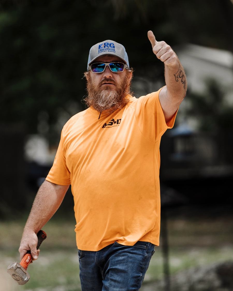 Dusty Tyer in an orange ASD shirt walking across a job site